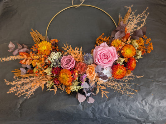 Decorative floral hoop with pink, orange, and purple flowers on a dark background